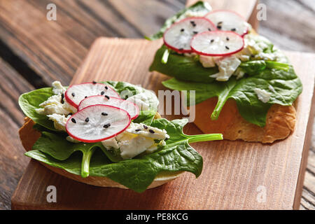 Bruschetta con ravanelli, spinaci e ricotta con semi di lino su uno sfondo di legno. Foto Stock