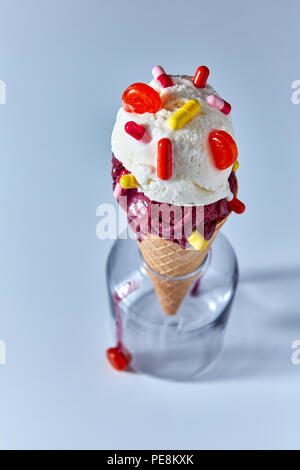 Cono di cialda con diversi gelati sfere decorate con capsule di compresse in una bottiglia trasparente su uno sfondo blu. Vista superiore Foto Stock