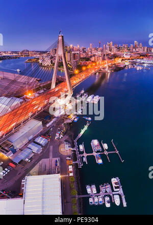 La città di Sydney ANZAC ponte sul porto durante il blu ora antenna in vista in elevazione su city marina verso CBD torri con illuminazione brillante. Foto Stock