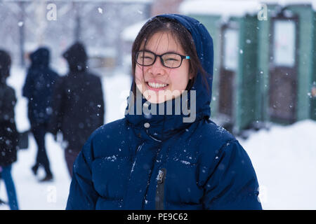 Felice giovani asiatici adolescente di sesso femminile nella spessa blu giacca invernale godetevi essendo esterno durante l'inverno la neve, buona per lo stile di vita felice o atteggiamento positivo co Foto Stock