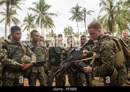 TANDUO BEACH, Malesia (nov. 10, 2015) DEGLI STATI UNITI Lancia Marine Cpl. Nicolas Biglione dimostra velocità ricarica di soldati malesi durante Malaysia-United membri Esercizio anfibio 2015. Biglione è una macchina gunner con Kilo Company, Battaglione Team di atterraggio 3° Battaglione, 1° Reggimento Marine, xv Marine Expeditionary Unit. Durante MALUS AMPHEX 15, Marines con il quindicesimo MEU e malese scambiati i soldati di fanteria le funzionalità di armi e tattiche. Lo scopo dell'esercizio è stato quello di rafforzare la cooperazione militare nella pianificazione ed esecuzione di operazioni di anfibio malese tra forze armate Foto Stock