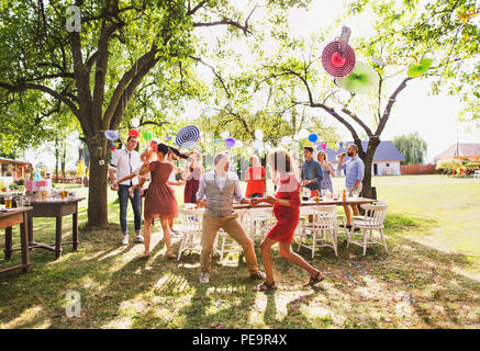 Un senior coppia e famiglia danza su un party in giardino al di fuori nel cortile. Foto Stock