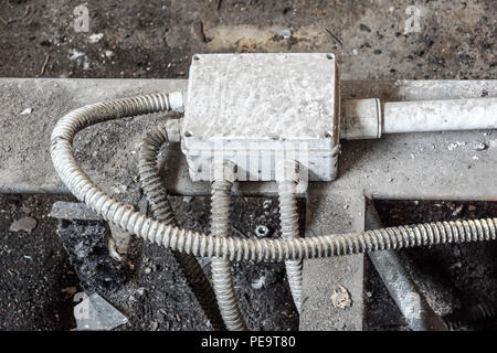 Bianco elettrico scatola con tre cavi neri sul vecchio rosso un muro di mattoni. Foto Stock