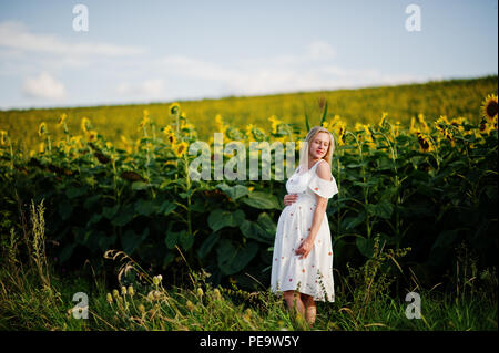 Bionda donna incinta nel campo di girasoli. Momenti felici di gravidanza. Foto Stock