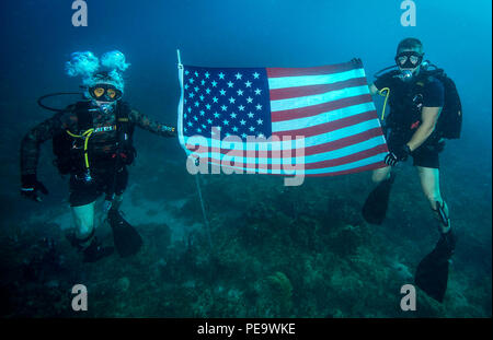 151119-N-WX059-113 Guantanamo Bay a Cuba (nov. 19, 2015) Navy Diver di terza classe Bryan Regan, sinistra e il Navy Diver 1a classe Troy Crowder, entrambi assegnati alla stazione navale di Guantánamo Bay Dive Locker, posano con la bandiera americana durante la fotografia subacquea formazione al largo della Baia di Guantanamo, Cuba, nov. 19, 2015. Combattimento Expeditionary fotocamere fotografia subacquea Team conduce corsi di formazione annuali per affinare la sua divers un insieme di competenze specializzate e di garantire un sostegno prezioso del dipartimento della difesa attiva in tutto il mondo. (U.S. Foto di Marina di Massa lo specialista di comunicazione 2a classe Sean Furey) Foto Stock