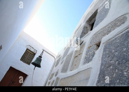 Foto inclinato di una campana della chiesa in uno degli stretti vicoli della Chora nell' isola di Astypalea, Grecia Foto Stock