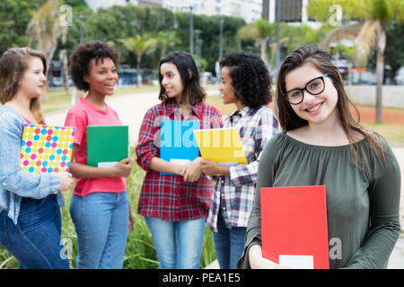 Francese studente femmina con un gruppo di studenti internazionali all'aperto sul campus della University Foto Stock