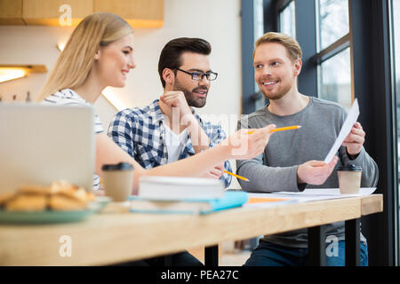 Il nostro lavoro. Smart bella giovani seduti insieme e guardando il documento durante la discussione Foto Stock