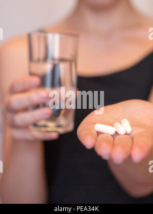 Close up girl holding pillola e bicchiere di acqua.con paracetamolo.I supplementi nutrizionali.Sport,la dieta concetto.capsule di vitamine e integratori alimentari. Foto Stock