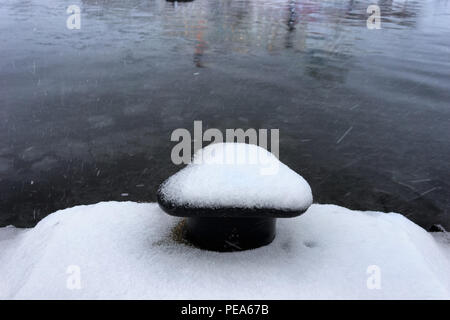Prima neve sul molo con un molo nella città portuale di Riga Foto Stock