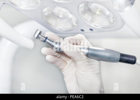 A braccetto con strumenti dentali per la foratura sullo sfondo delle luci presso la clinica Foto Stock