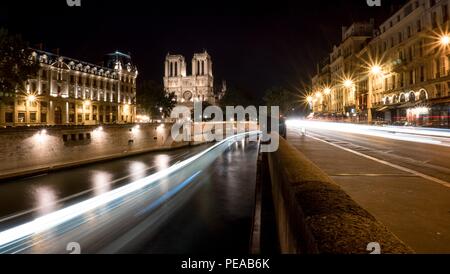La cattedrale di Notre Dame di Parigi di notte con luci sentieri nel fiume Senna e la qua d'Orleans Foto Stock