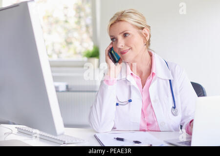 Colpo di belle donne anziane medico utilizzando il telefono cellulare e la consultazione con il suo paziente. Foto Stock