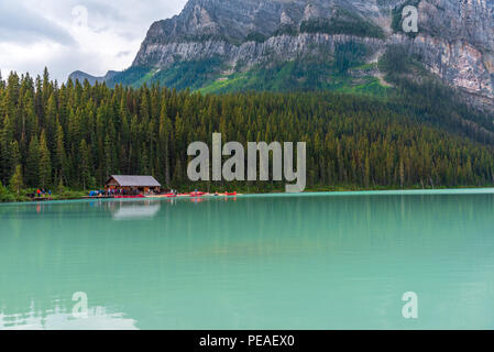 Banff, Canada -- Agosto 03, 2018. I barcaioli preparare alla paletta sul turquise acque del Lago Louise in Banff, Canada con montagne Rockie loomin Foto Stock