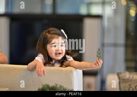 Due anni di bambina gioca in piedi su un lettino Foto Stock