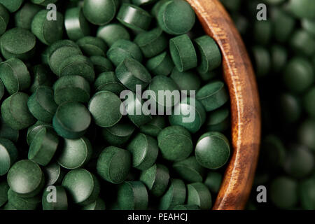 Vista ravvicinata della ciotola di legno con palo di spirulina pillole Foto Stock