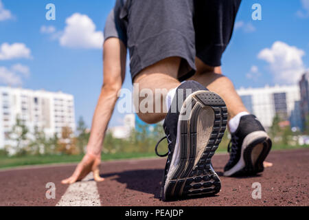 Vista posteriore close up di un irriconoscibile sportivo nella posizione di partenza pronta per eseguire all'aperto, spazio di copia Foto Stock