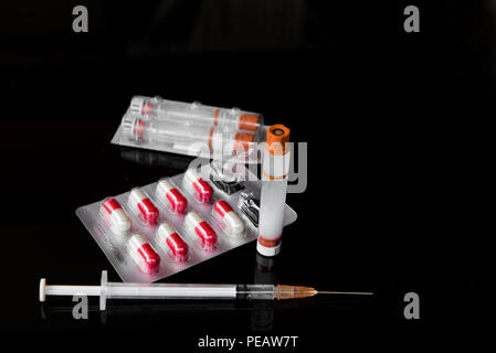Siringa di diabete e capsule farmaco su sfondo nero Foto Stock