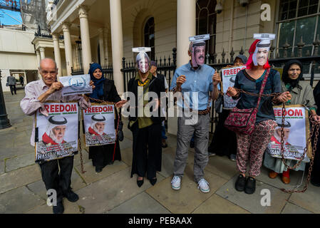 Agosto 13, 2018 - Londra, Regno Unito. Il 13 agosto 2018. La breve strada spettacolo teatrale termina con i manifestanti di maschere per "fornitore di armi Theresa Maggio", macellaio del Bahrain Hamid Khalifa' e 'Little Stooge Fawaz Khalifa' in catene e che vengono adottate per il Tribunale penale internazionale per i crimini commessi contro la popolazione del Bahrain. I manifestanti hanno sfidato la polizia che ha detto loro che essi non possono protestare sul marciapiede fuori del Bahrain ambasciata a sostegno di scioperante della fame Ali Mushaima chi è stato al di fuori del Bahrain ambasciata in Belgrave Square dal 1 agosto, chiedendo il suo 70-anno vecchio padre in priso Foto Stock