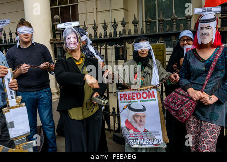 Agosto 13, 2018 - Londra, Regno Unito. Il 13 agosto 2018. Una donna con un ''fornitore di armi Theresa Maggio" Maschera dimostra come molto più efficace elettrici metodi di tortura sono a occhi bendati gli Stati del Pacifico opoosition del Bahrein con pinze in una breve strada spettacolo teatrale sfidando le forze di polizia che hanno detto loro che non possono protestare sul marciapiede fuori del Bahrain ambasciata a sostegno di scioperante della fame Ali Mushaima chi è stato al di fuori del Bahrain ambasciata in Belgrave Square dal 1 agosto, chiedendo il suo 70-anno vecchio padre in prigione in Bahrain per essere dato ha urgentemente bisogno di cure mediche, famiglia v Foto Stock