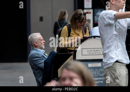 Stoke-on-Trent, Regno Unito. 14 Agosto 2018 - leader laburista Jeremy Corbyn a Stoke-on-Trent stazione ferroviaria. Egli è visto di contenimento monouso una tazza di caffè, mentre un membro del suo team porta una Staffordshire potteries vaso - una chiave per l'esportazione della città. Credito: Benjamin Wareing/Alamy Live News Foto Stock