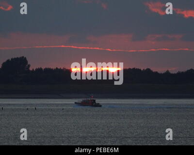 Sheerness, Kent, Regno Unito. 14 Ago, 2018. Regno Unito Meteo: la barca del pilota passa il sole di setting in Sheerness, Kent. Credito: James Bell/Alamy Live News Foto Stock