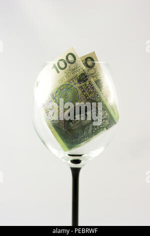 Due banconote di un centinaio di zlotys polacco all'interno del bicchiere di vino Foto Stock