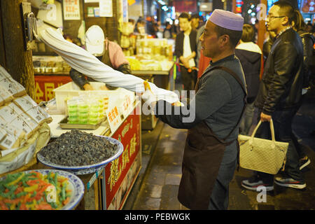 Un uomo di torsione di pasta in un mercato all'aperto, Musulmana Street, Xian, Shaanxi, Cina Foto Stock