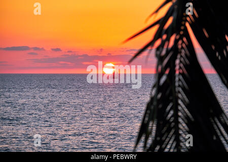 Barca a vela passando attraverso il disco del sole di setting, Banderas Bay, Jalisco, Messico. Foto Stock