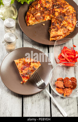 La tortilla de patatas. Frittata spagnola con salsiccia chorizo, patate, paprica e uovo, accompagnato da olio d'oliva. La cucina spagnola. Vista dall'alto. Foto Stock