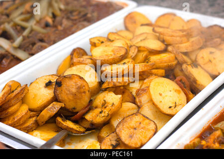 Patate al forno le fette su vassoio bianco con un cucchiaio Foto stock -  Alamy