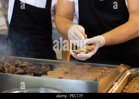 L'uomo le patatine fritte di carne Hamburger e cotolette su una griglia di cottura a vapore Foto Stock