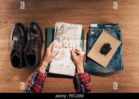 Vista in pianta parziale della persona in possesso di mappa e traveler impostato sul tavolo di legno Foto Stock