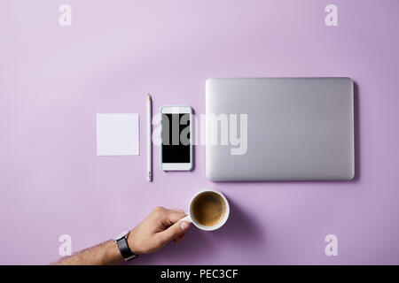 Ritagliato colpo di Uomo che piega tazza di caffè al lavoro sulla superficie di rosa per il mockup Foto Stock