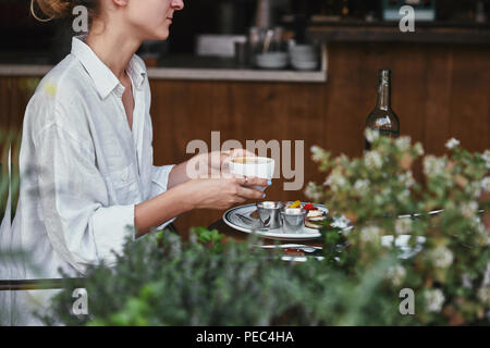 Ritagliato colpo di giovane donna azienda tazza di caffè presso il ristorante Foto Stock