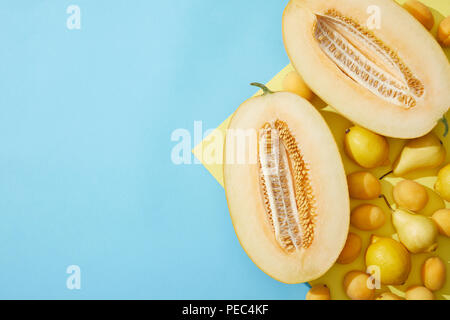 Vista superiore del dolce melone maturo, le pere, i limoni e le albicocche su giallo e blu Foto Stock