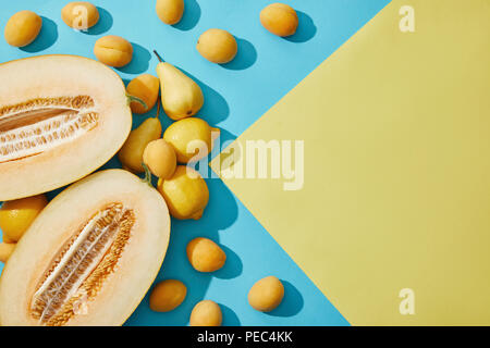 Dolce di melone maturo, le pere, i limoni e le albicocche su giallo e blu Foto Stock