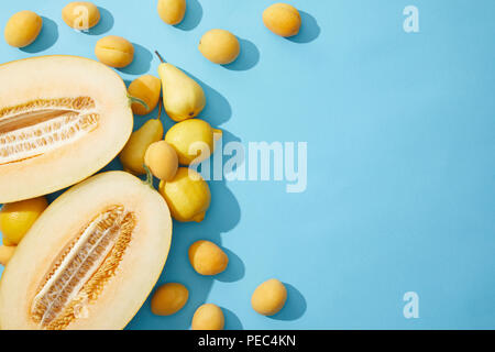 Vista superiore del fresco melone maturo, le pere, i limoni e le albicocche su sfondo blu Foto Stock