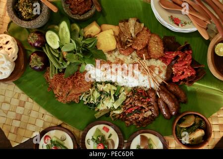 Rijsttafel indonesiano sulla foglia di banano. Riso con vari piatti da Sumatra, Java e Sulawesi sono servite su tutta la foglia di banano. Foto Stock