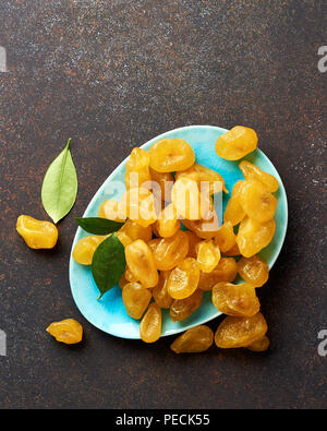 Giallo essiccato kumquat con foglie verdi su sfondo marrone. Vista dall'alto. Foto Stock