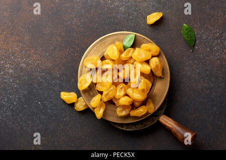 Giallo essiccato kumquat con foglie verdi su sfondo marrone. Vista dall'alto. Foto Stock