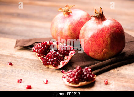 Frutti di melograno con grani sul tavolo di legno. Foto Stock
