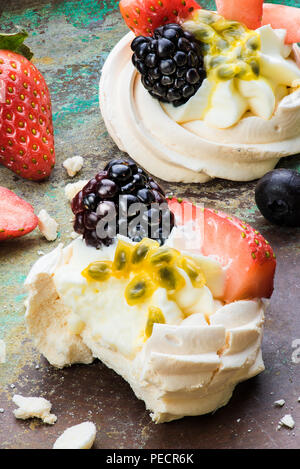 Mini Pavlova meringa torte con bacche e frutti della passione sul rustico sfondo vintage. Vista dall'alto. Foto Stock