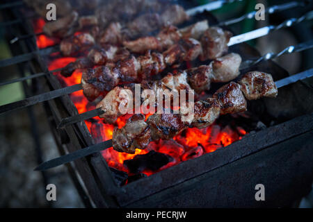 Spiedini preparazione su un grill barbecue a carbone. Pezzi di carne su spiedini. Shish kebab preparare sul fuoco. Foto Stock