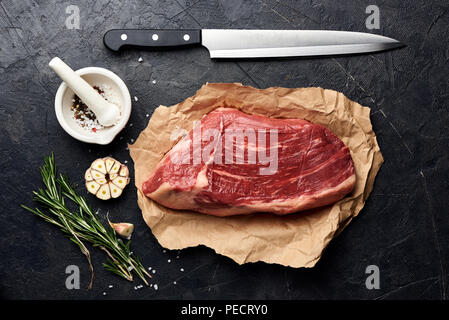 Crudo fresco di carne in marmo nero bistecca angus e coltello di carne. Foto Stock