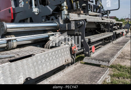 Dettagli di asfalto lastricatore macchina durante la costruzione di strade e lavori di riparazione. Un lastricatore finisher, asfalto di finitura o macchina di pavimentazione disporre uno strato di asfalto. Ripavimentazione Foto Stock