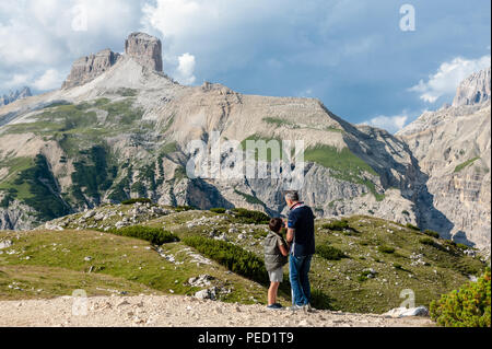 Papà insegnare a suo figlio di scattare una foto delle Alpi italiane, vicino alle Tre Cime nelle Dolomiti, in un pomeriggio d'estate. Foto Stock