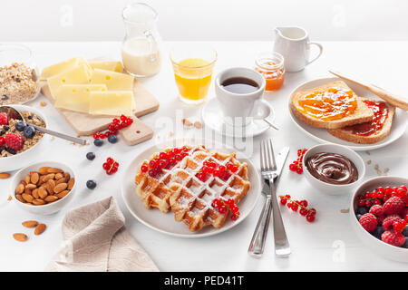 La prima colazione con muesli dadi berry, waffle, toast, marmellata, cioccolata spalmabile e caffè Foto Stock