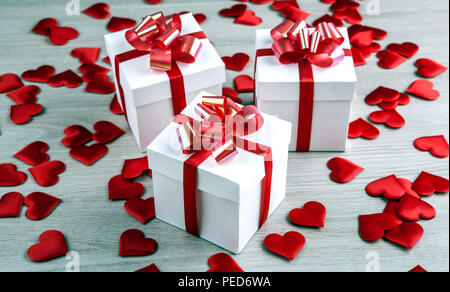 Tre bianchi confezioni regalo su uno sfondo grigio e cuore tessili forme close up Foto Stock