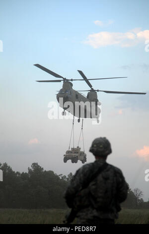 Un paracadutista dell'esercito del 1st Battalion, il 508th Parachute Infantry Regiment osserva un elicottero Boeing CH‑47 Chinook della 82nd Combat Aviation Brigade che solleva un Humvee con un carico di imbracatura esterno durante le operazioni di attacco aereo e trasporto coordinate a Fort Bragg, Carolina del Nord. Il Chinook a rotore tandem, progettato per il sollevamento pesante e il movimento delle truppe con due motori turboalbero Honeywell T55, supporta un rapido dispiegamento e esercizi di grippaggio oggettivi per le unità di fanteria aviotrasportate. :ContentReference[oaicite:0]{index=0} Foto Stock